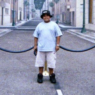 Boy stands on a street resembling Hollywood Boulevard.