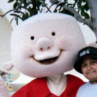 Man poses with a pig character at an outdoor location.