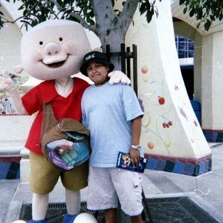 Man poses with a pig character at an outdoor location.