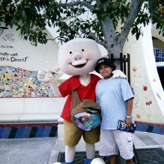 Man poses with a pig character at an outdoor location.