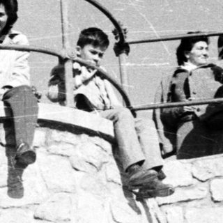 People sit on a stone tower, posing for a photo.
