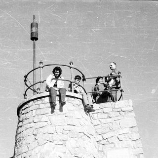 People sit on a stone tower, posing for a photo.