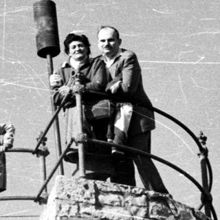 People pose on a stone tower with a bell.