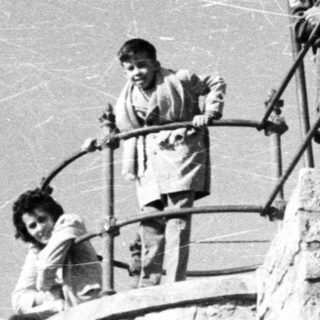People pose on a stone tower with a bell.