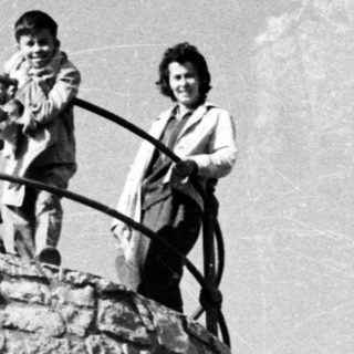 Three children stand atop a stone tower with a device.