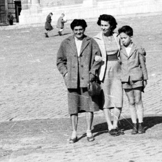 Black and white photo of people standing in front of a building.