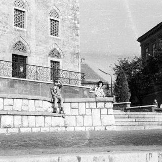 People seated on steps in front of a building.