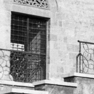 People seated on steps in front of a building.