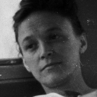 Here's a brief summary of the image: Woman in bed, looking out a window.