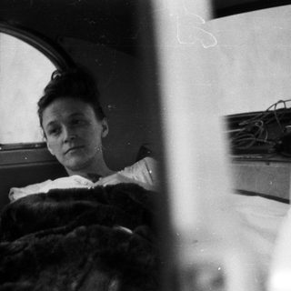 Here's a brief summary of the image: Woman in bed, looking out a window.