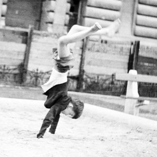Boy performs a handstand in front of a building.