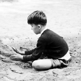 Here's a brief summary: Boy seated, playing in dirt beside a curb.