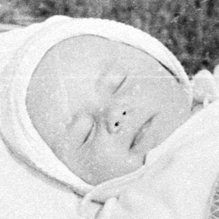Baby sleeping in a vintage pram outdoors.