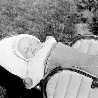 Baby sleeping in a vintage pram outdoors.