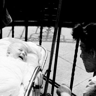 Baby in a pram, smiling, being pushed along.