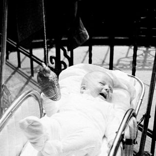 Baby in a pram, smiling, being pushed along.
