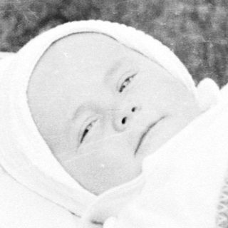 Baby in a vintage stroller, resting in the grass.