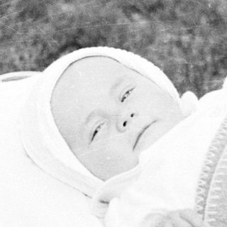 Baby in a vintage stroller, resting in the grass.