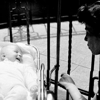 Baby in a pram, with a woman nearby.