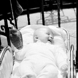 Baby in a pram, with a woman nearby.