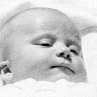 Infant sleeping peacefully in a vintage baby carriage.