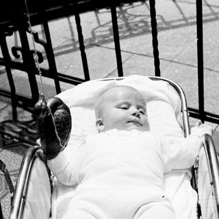 Infant sleeping peacefully in a vintage baby carriage.