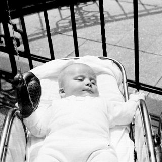 Infant sleeping peacefully in a vintage baby carriage.