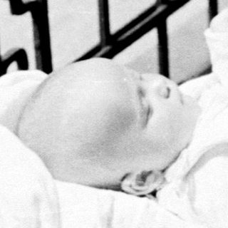 Baby sleeps peacefully in an antique baby carriage.
