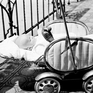 Baby sleeps peacefully in an antique baby carriage.