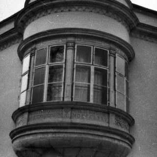 Black and white photo of a bay window with balcony.