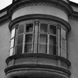 Black and white photo of a bay window with balcony.