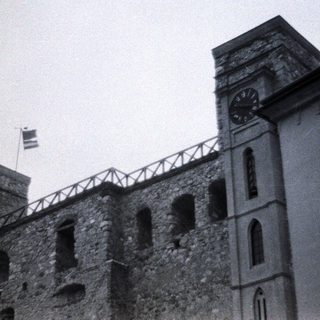 Stone building with clock tower and flag.