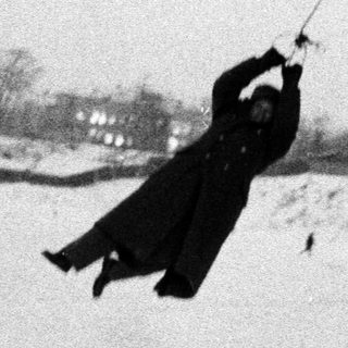Person swings across a snowy landscape in a vintage scene.