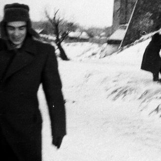 Man stands near children playing in snowy landscape.