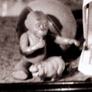 Figurines near a vintage record player on a textured floor.