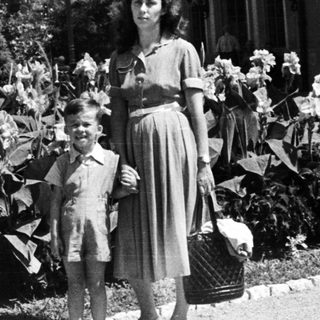 Woman and boy standing in a garden, holding a basket.