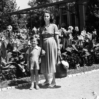 Woman and boy standing in a garden, holding a basket.