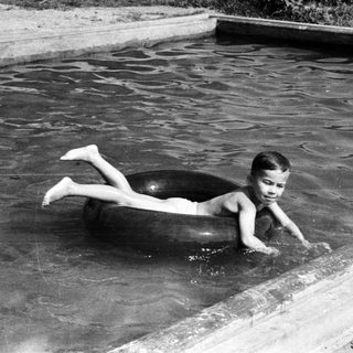 Boy floats in a pool on an inner tube.