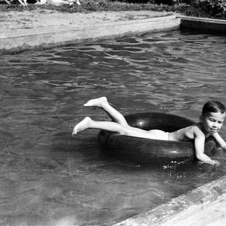 Boy floats in a pool on an inner tube.
