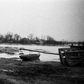 Flooded landscape with a boat and damaged wooden structure.
