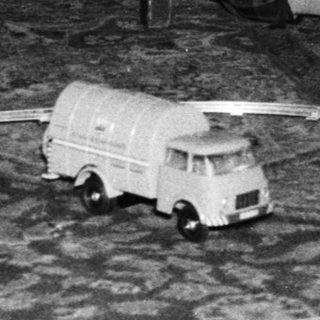 Boy plays with toy train set near Christmas tree.