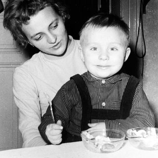 Girl and young boy seated at a table with food.