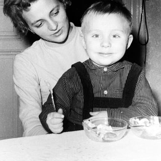Girl and young boy seated at a table with food.