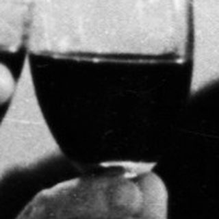 Two men in suits are toasting with glasses of wine.