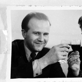 Two men in suits are toasting with glasses of wine.