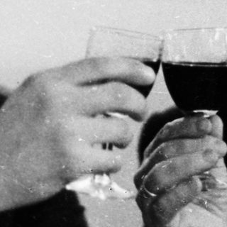 Two men in suits are toasting with glasses of wine.