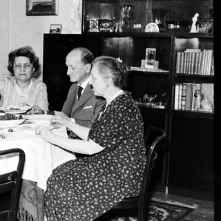 Here's a brief summary of the image: Four people seated at a table, having a meal.