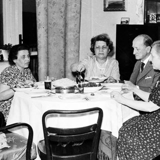 Here's a brief summary of the image: Four people seated at a table, having a meal.