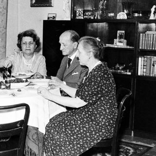 Here's a brief summary of the image: Four people seated at a table, having a meal.