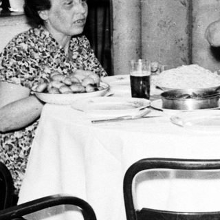 Here's a brief summary of the image: Four people seated at a table, having a meal.